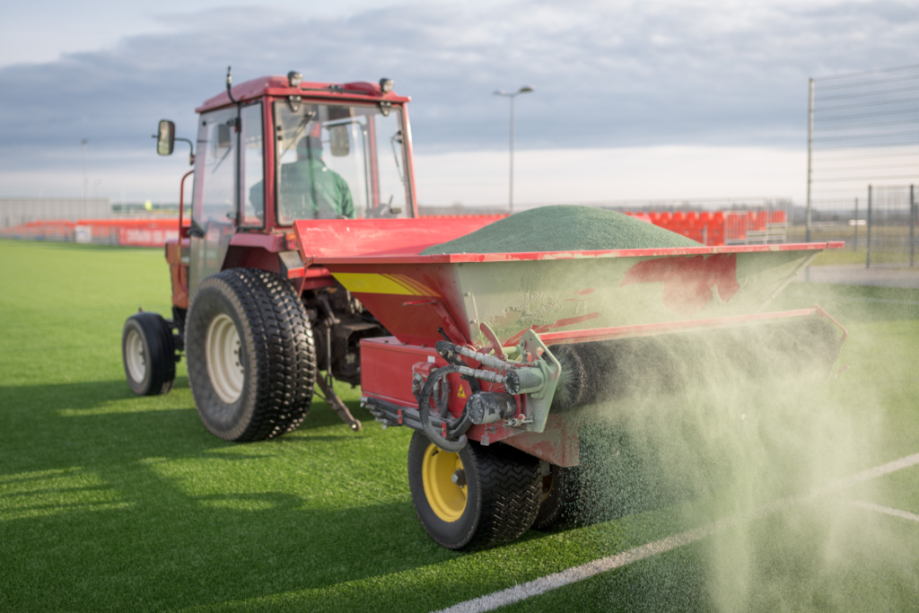 a picture of a tractor spreading turf infill.